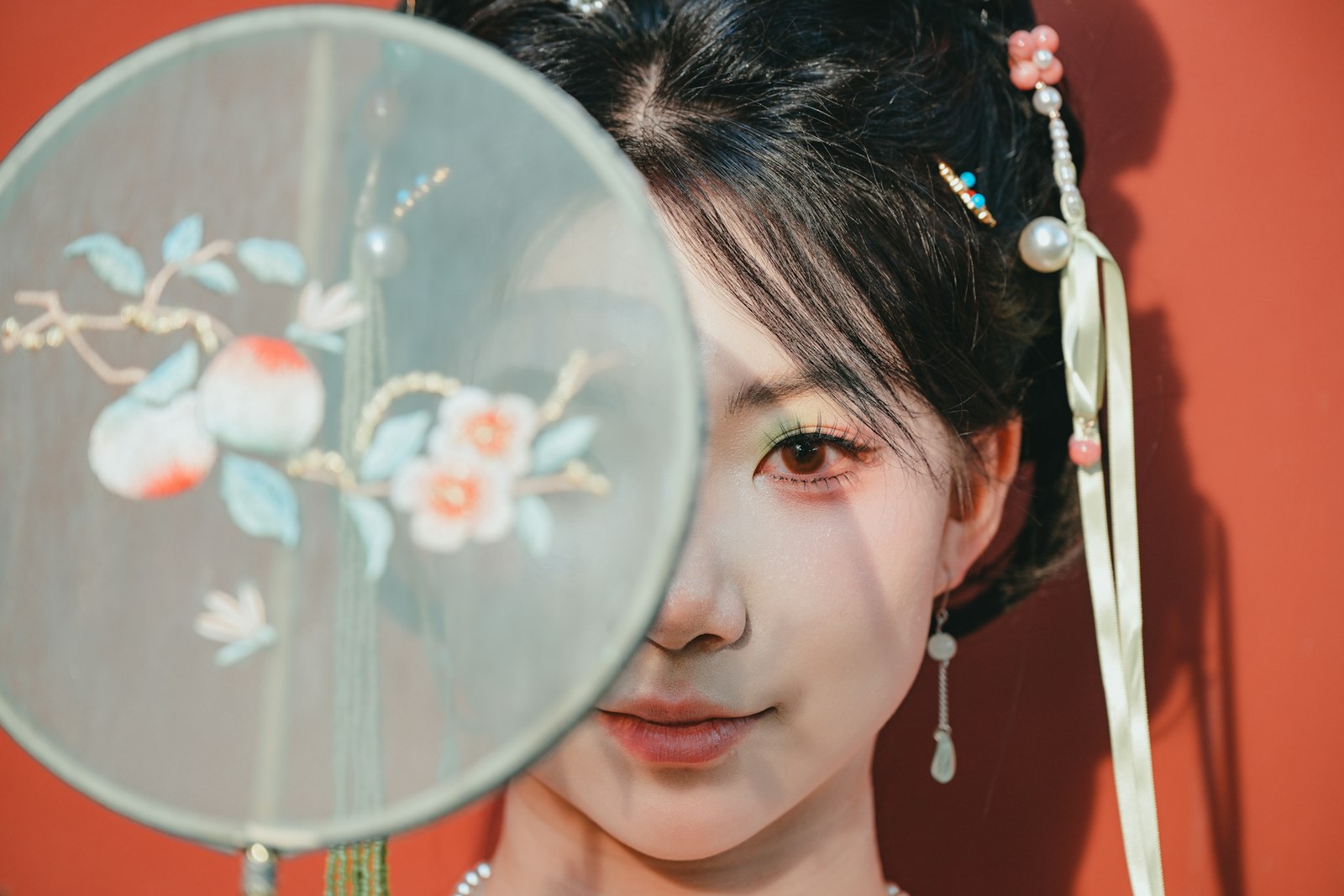 Young woman in traditional Chinese court attire holding an embroidered fan