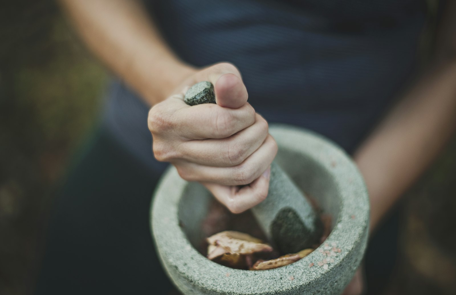 Hands grinding herbs in a stone mortar and pestle, like apothecary Maomao