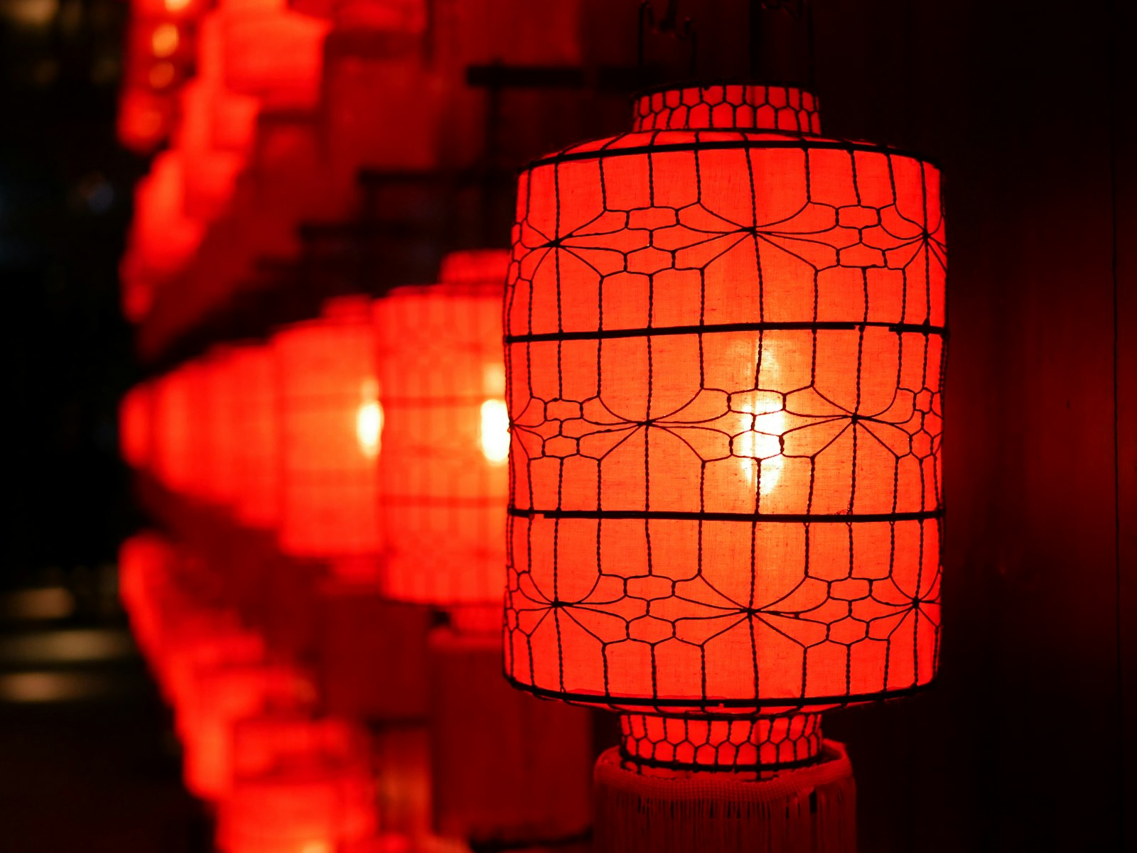 Glowing red paper lanterns at night, evoking the pleasure district and Verdigris House